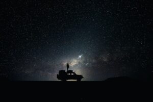 Silhouette einer Person auf einem Geländewagen unter einem Sternenhimmel
