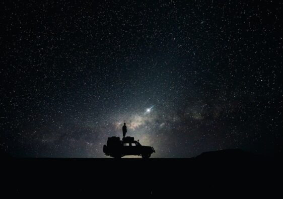 Silhouette einer Person auf einem Geländewagen unter einem Sternenhimmel
