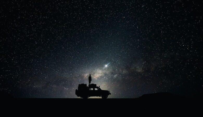 Silhouette einer Person auf einem Geländewagen unter einem Sternenhimmel