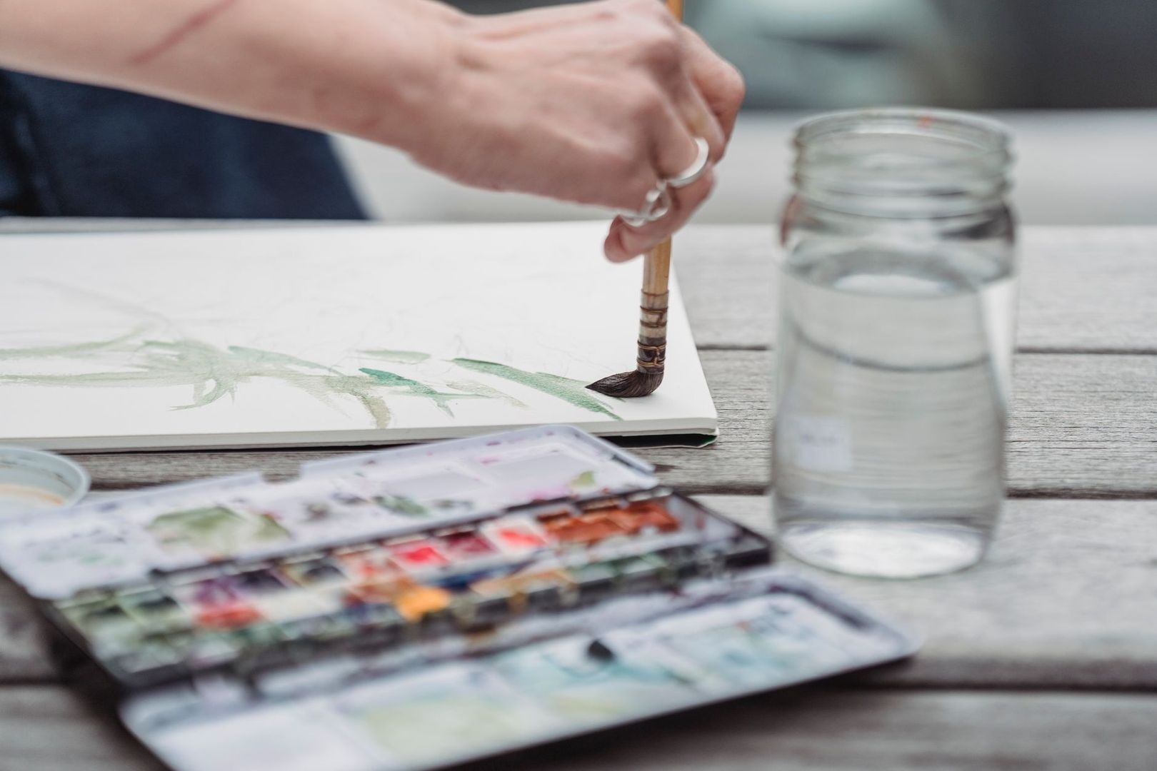 Hand malt mit Pinsel und Aquarellfarben in einem Skizzenbuch